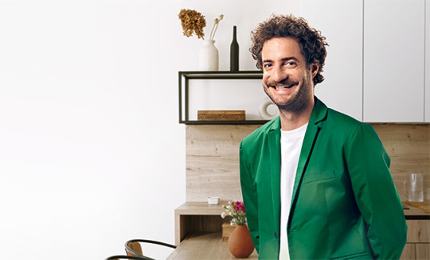 Hausratversicherung – Mann in grünem Anzug steht in Wohnküche